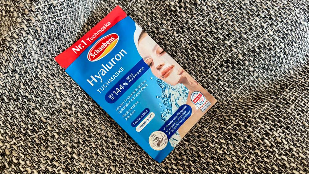 Eine Packung der Hyaluron-Tuchmaske im Test liegt leicht schräg auf einem Polster.
