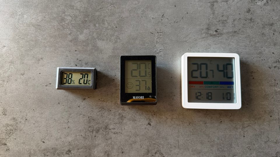Drei Hygrometer liegen nebeneinander auf einem Tisch