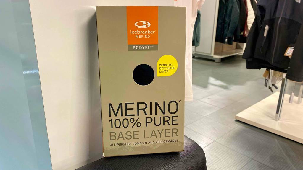 Lange-Unterhose-Herren-Test: In einem Bekleidungsgeschäft steht eine Verpackung mit getesteten langen Unterhosen für Herren aus 100 % schwarzer Merinowolle auf einem Hocker.