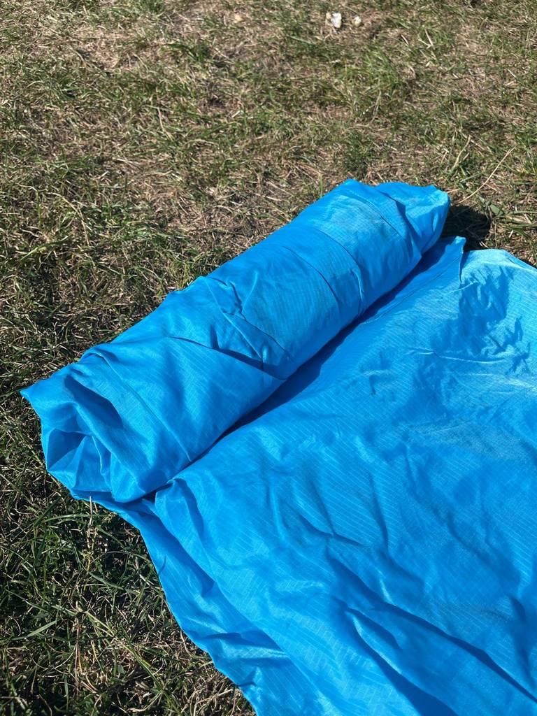 Ein zusammengerolltes Luftsofa im Test liegt auf einem Rasen.
