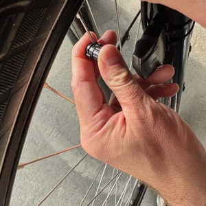 Eine Hand hält den Magneten des Icocopro West Biking an eine Speiche eines Fahrrads