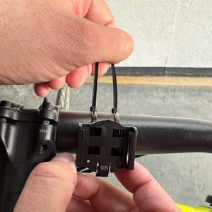 Eine Hand zieht die Kabelbinder am Halter des Displays des Icocopro West Biking fest