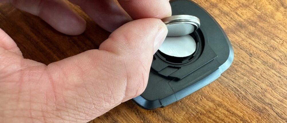 Eine Hand setzt eine Knopfbatterie in das Display des Icocopro West Biking