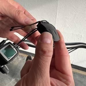Eine Hand hält Kabelbinder an den Halter des Empfänger des Icocopro West Biking