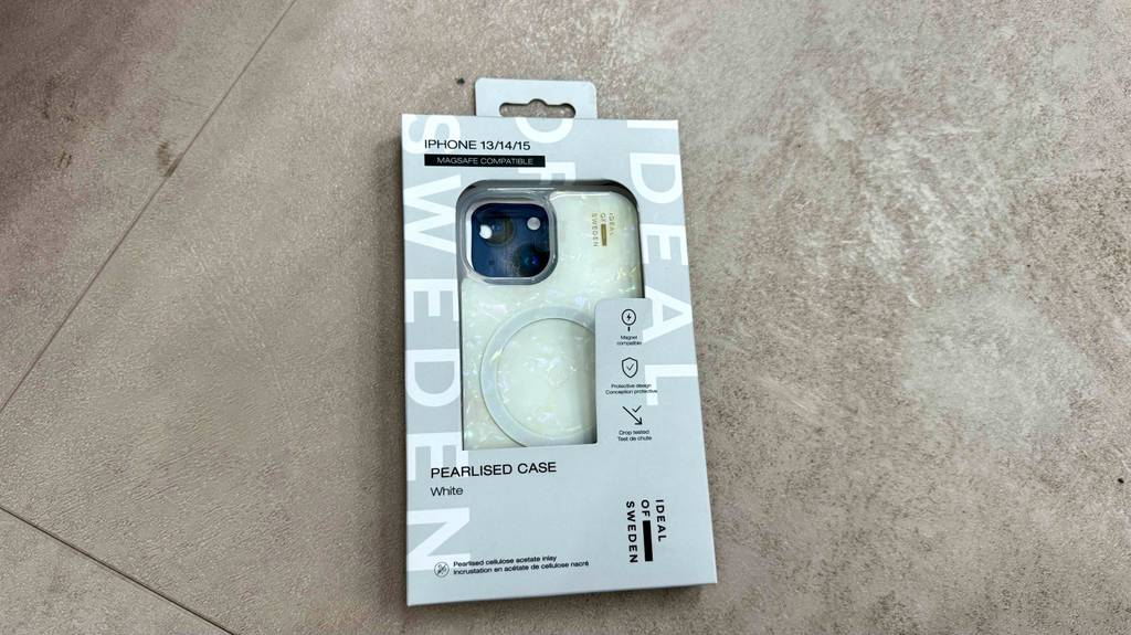 iPhone-14-Hüllen im Test: Eine Perlmutt-Ausführung in der Verpackung liegt auf einer grauen Oberfläche.