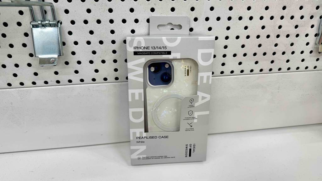 iPhone-14-Hüllen-Test: Eine Perlmutt-Ausführung in der Verpackung lehnt an einer gelochten Wand.