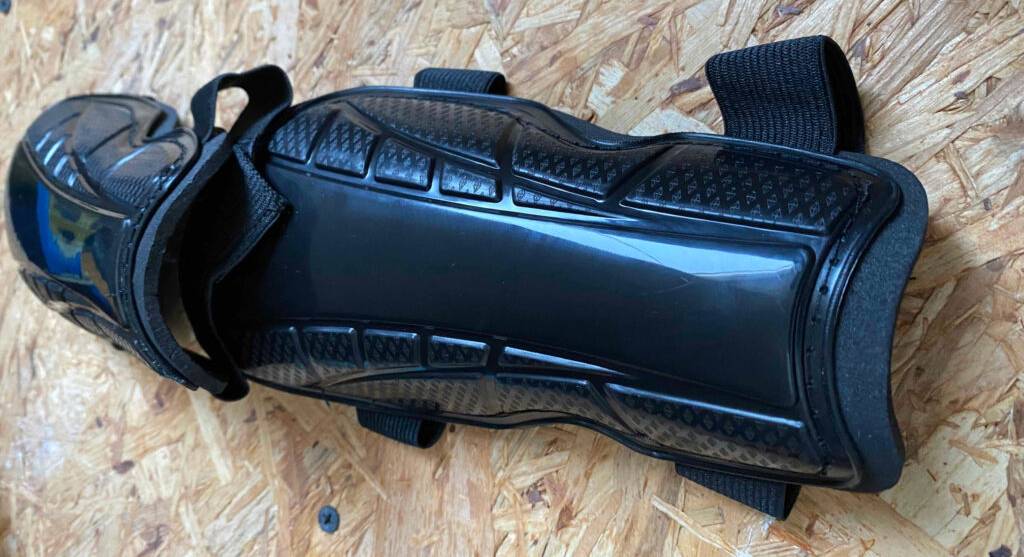 Ein Paar schwarzer Schienbeinschoner im Test liegen auf einer Holzoberfläche.