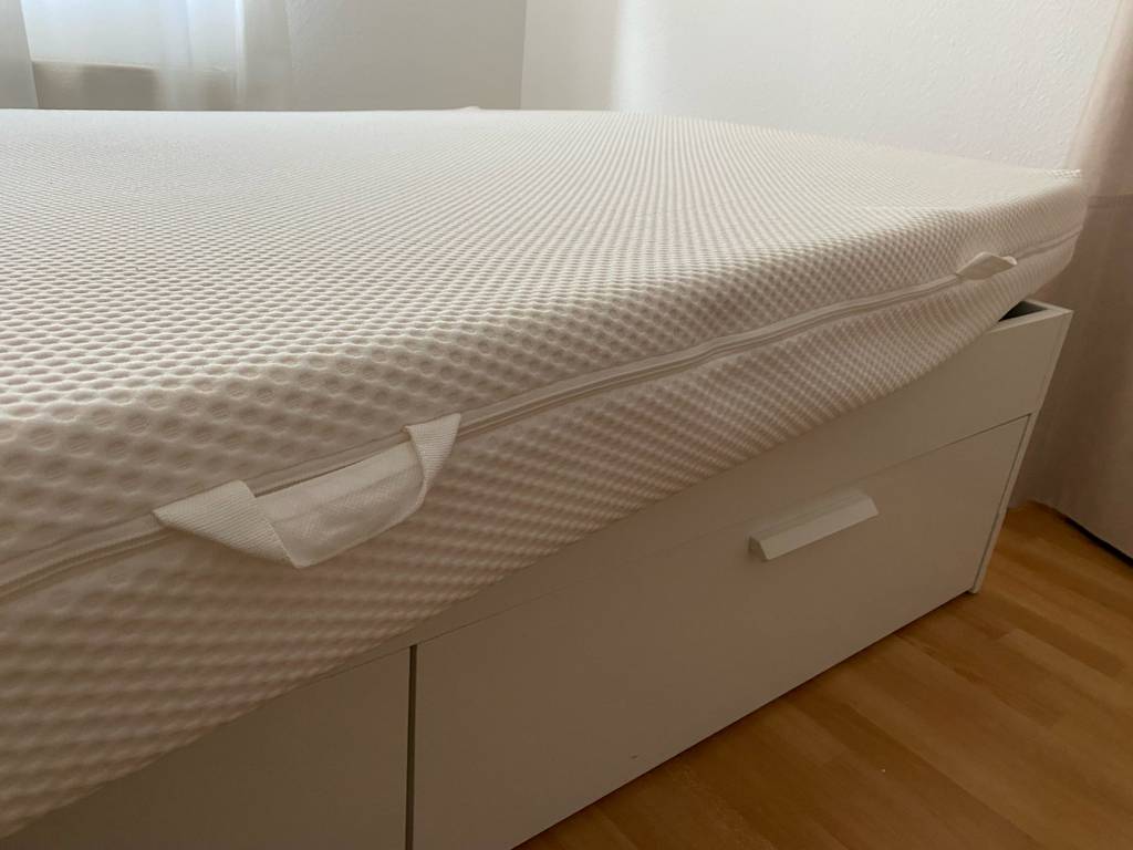 Matratze 160 x 200 cm im Test: Eine Matratze in einem Bett von der Seite mit den Haltegriffen.