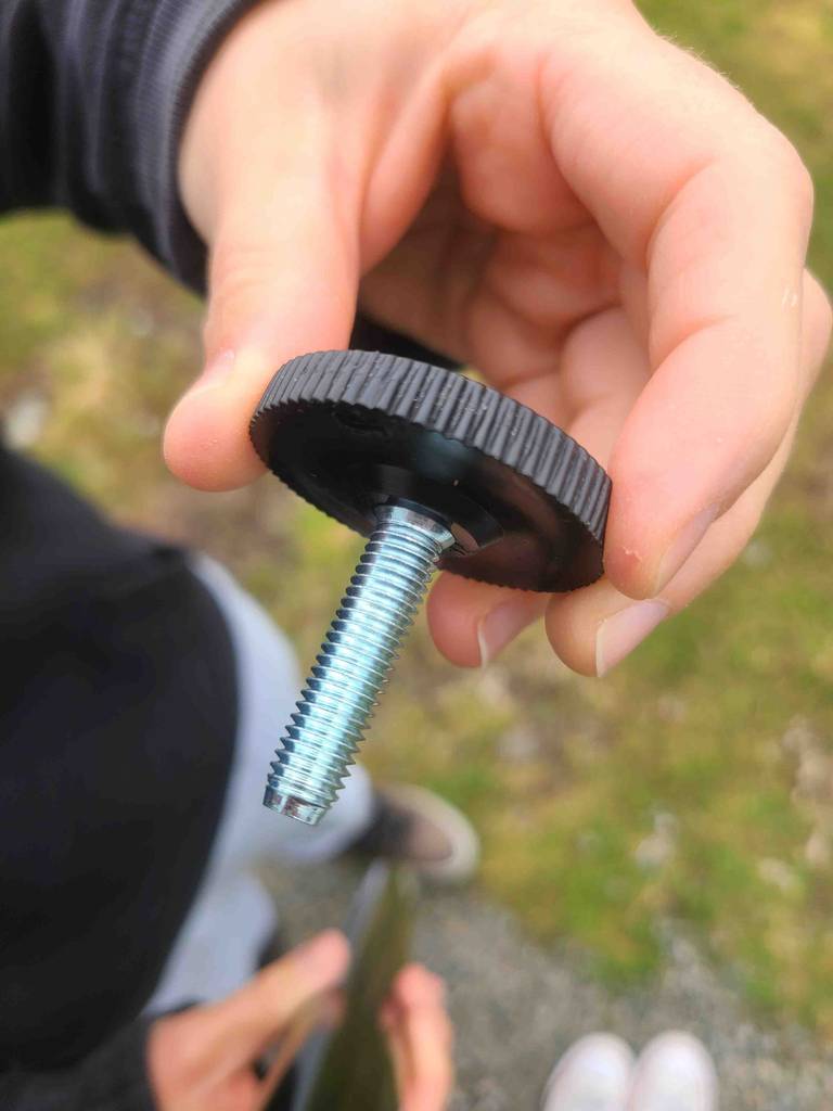 Eine Hand zeigt den rutschfesten Fuß inklusive Schraube von dem getesteten Metall-Tischbein.