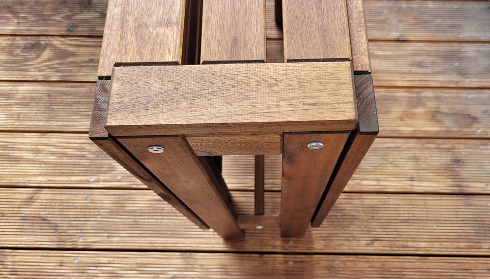 Nahaufnahme von einem zusammengeklappten Gartentisch aus Holz im Test von oben auf Holzboden.