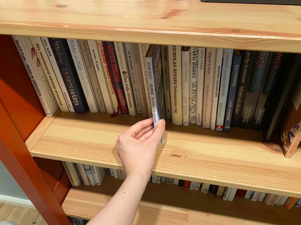 Hand nimmt ein Buch aus einem getesteten Bücherregal.