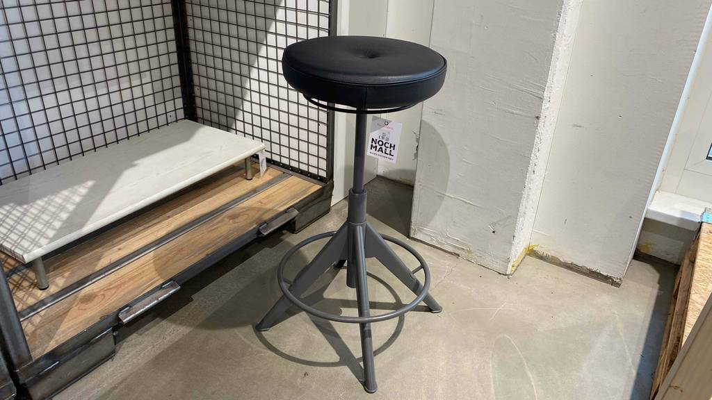 Bürohocker im Test: Ein Hocker steht vor einem Hochregal auf einem Steinboden.