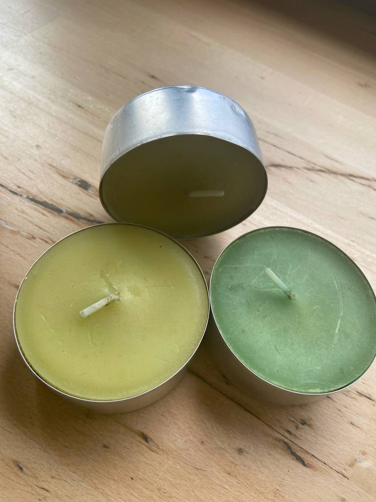 Detailansicht des Materials von getesteten Duft-Teelichtern, eines steht aufrecht hinter den anderen.