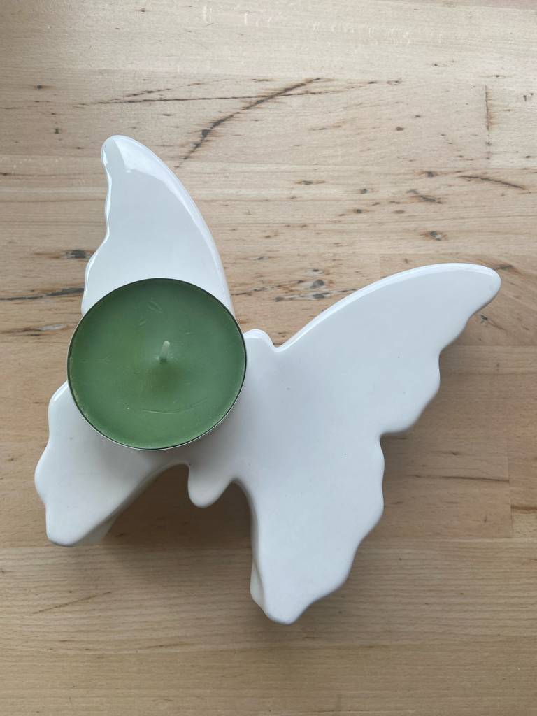 Duft-Teelichter getestet: Ein Teelicht steht auf einem Porzellanschmetterling.