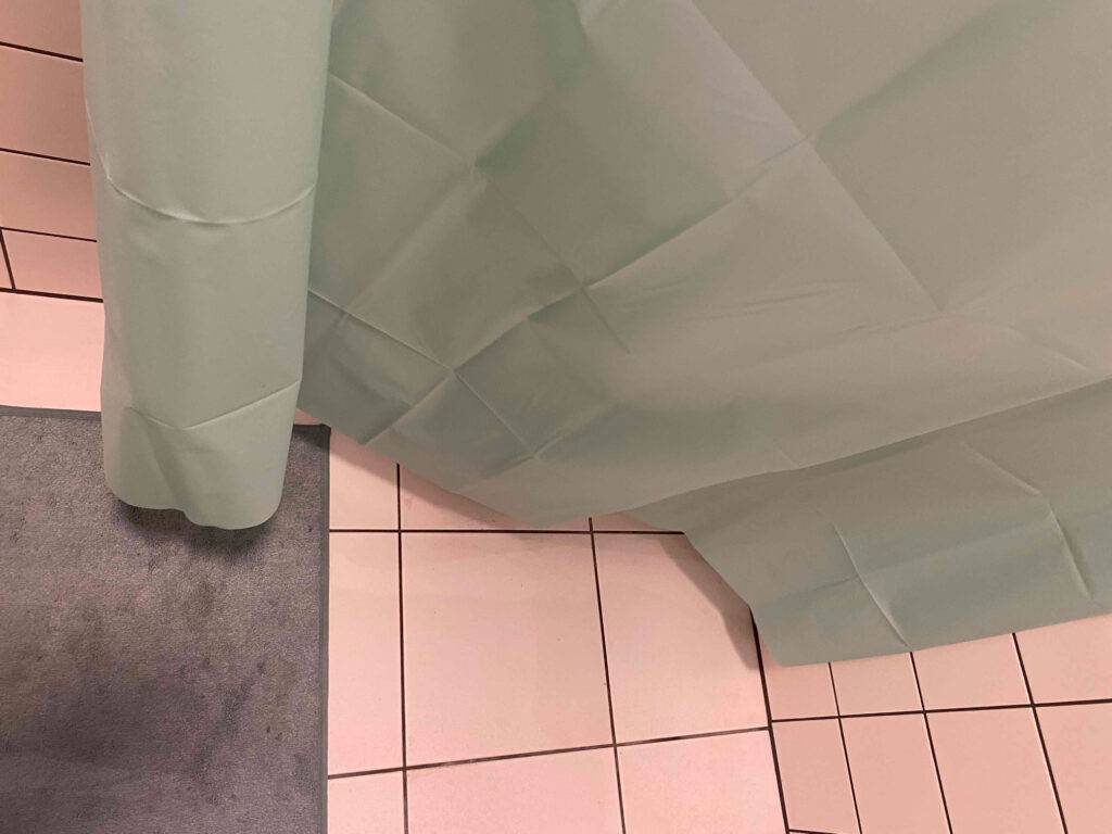 Ansicht auf den unteren Rand eines getesteten Duschvorhangs in Olivgrün.