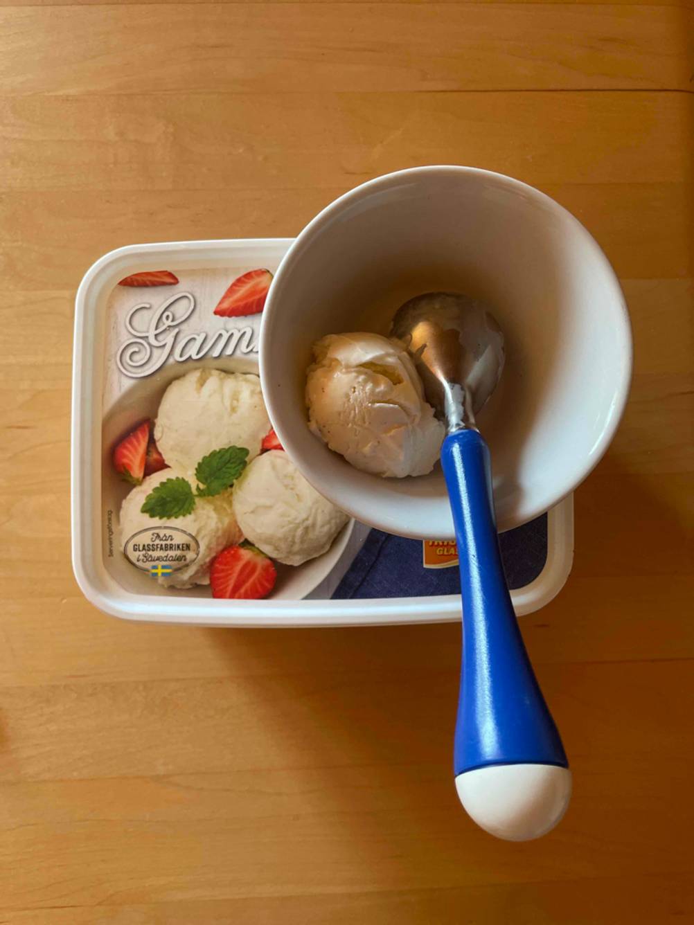 Eisportionierer im Test: ein Modell mit blauem Handgriff liegt in einer weißen Schale, die auf einer Verpackung mit Eis steht.