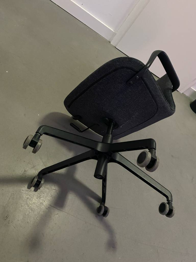 Ein dunkelgrauer, getesteter ergonomischer Bürostuhl liegt auf einem grauen Zementboden.