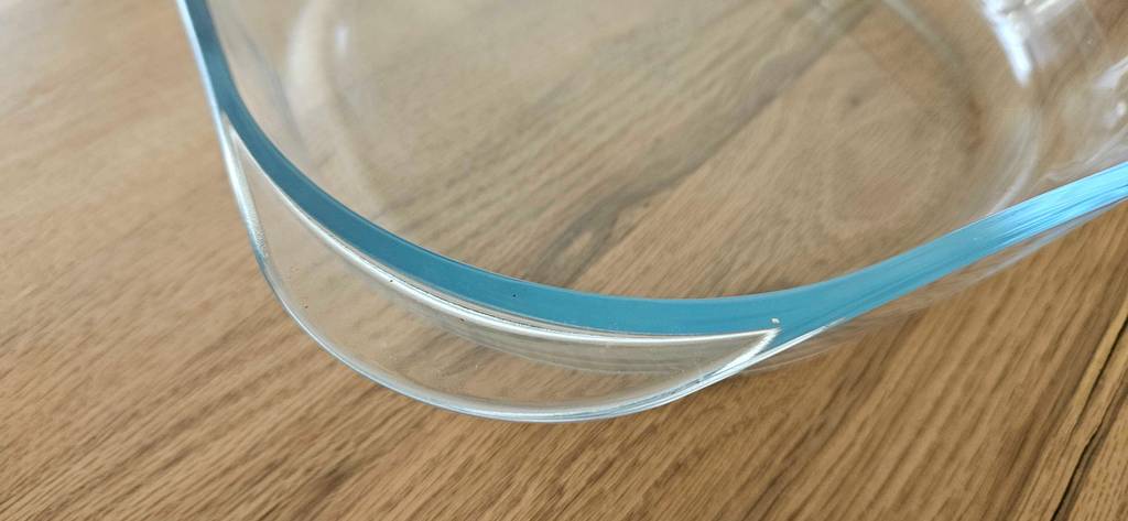 Detailansicht des Griffs an einer abgerundeten Ecke von einer Glas-Auflaufform im Test auf einer Holztischplatte.