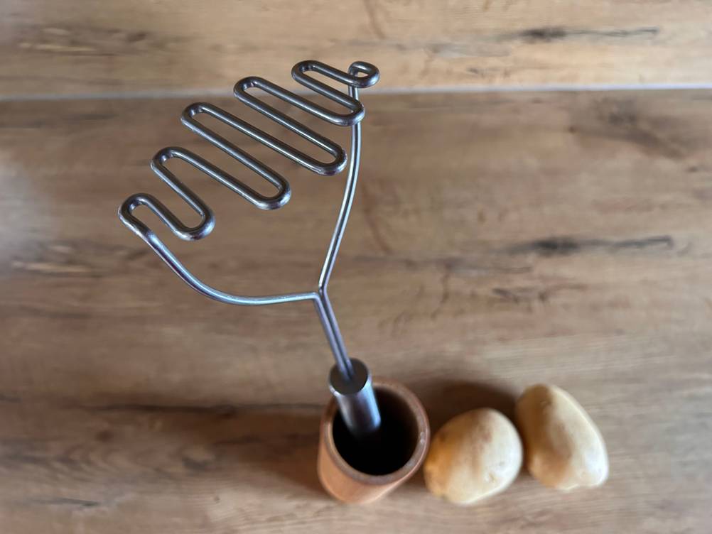 Ein getesteter Kartoffelstampfer steht auf einer Kartoffel, von oben betrachtet.