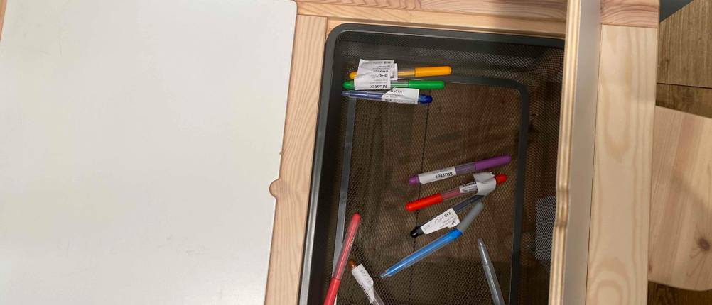 Kindertisch im Test: Unter einer aufgeklappten Hälfte befindet sich ein versenkter Aufbewahrungskorb.