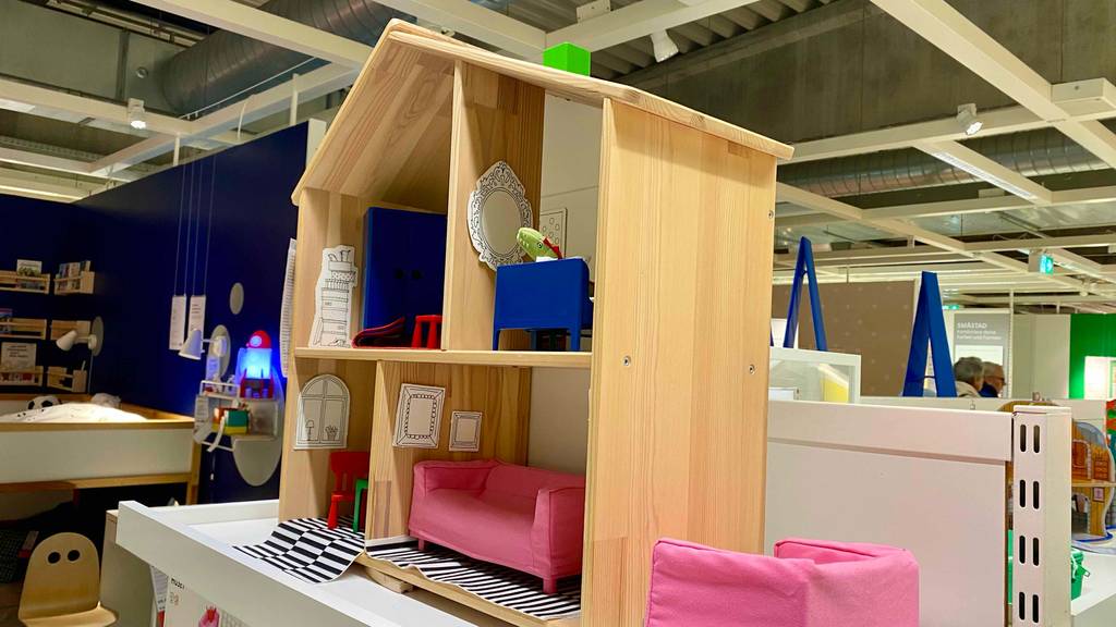 Puppenhaus im Test: Seitenansicht von vorn auf ein helles Holzpuppenhaus inklusive vier möblierter Zimmer.