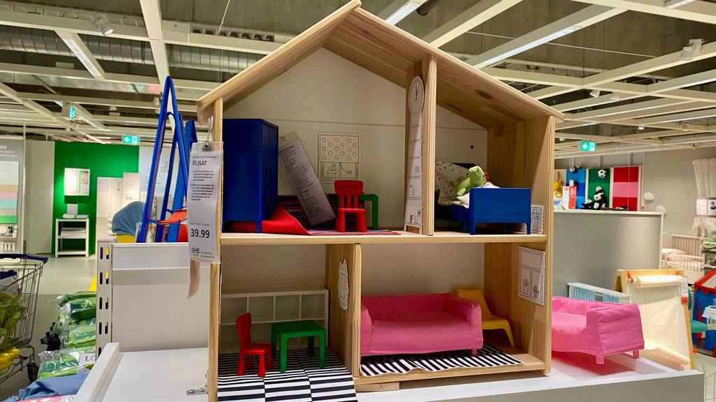 Puppenhaus-Test: Gesamtansicht von vorn auf ein Holzpuppenhaus mit vier Zimmern, ausgestellt in einem Verkaufsbereich.