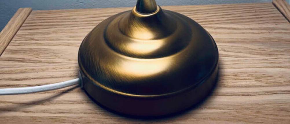 Schreibtischlampe getestet: Standfuss in Nahaufnahme auf einer Holzfläche.