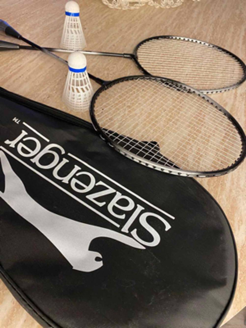 Zwei Metall-Schläger und zwei Federbälle des getesteten Federball-Sets liegen einer schwarzen PVC- und Stofftragetasche.