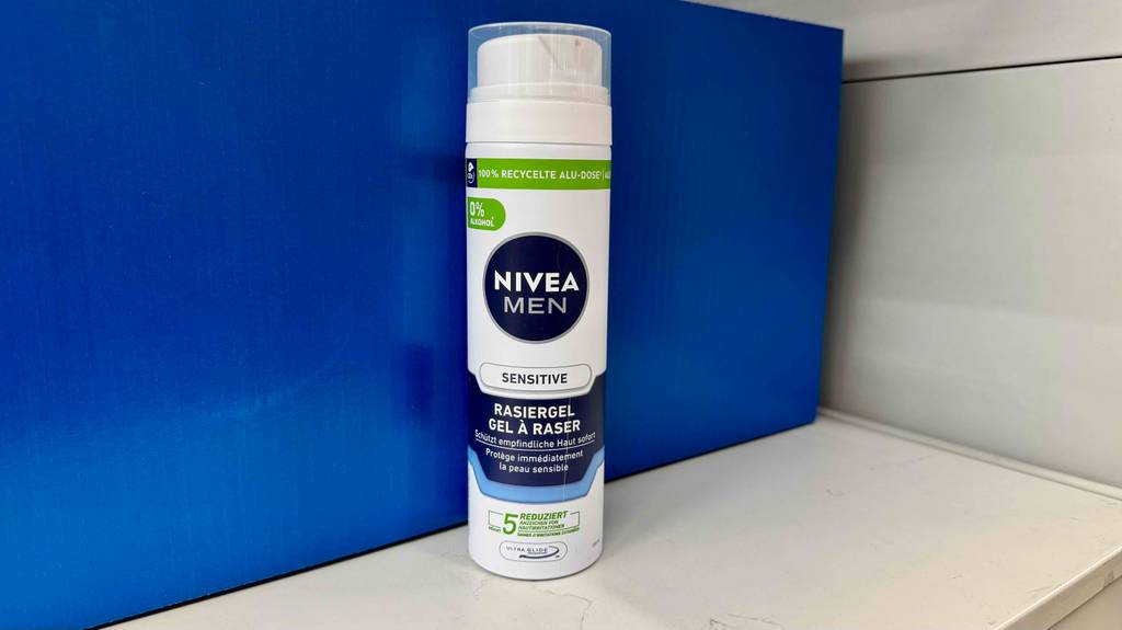 Vor einer blauen Schachtel steht eine recycelte Dose mit getestetem Nivea-Rasierschaum.