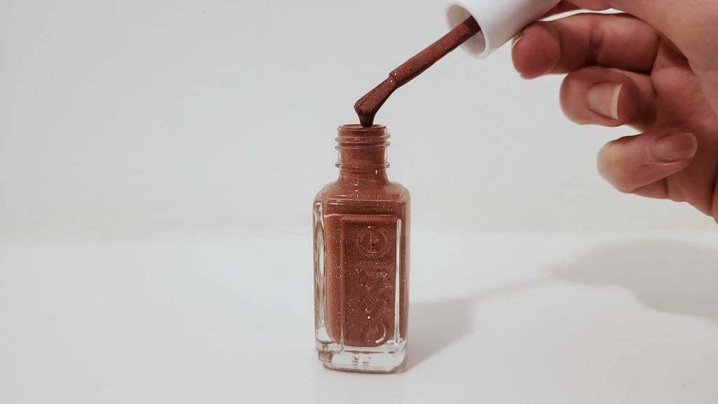 Im Test: Essie-Nagelack, der sich über der Flasche auf einem Pinsel in einer Damenhand befindet.