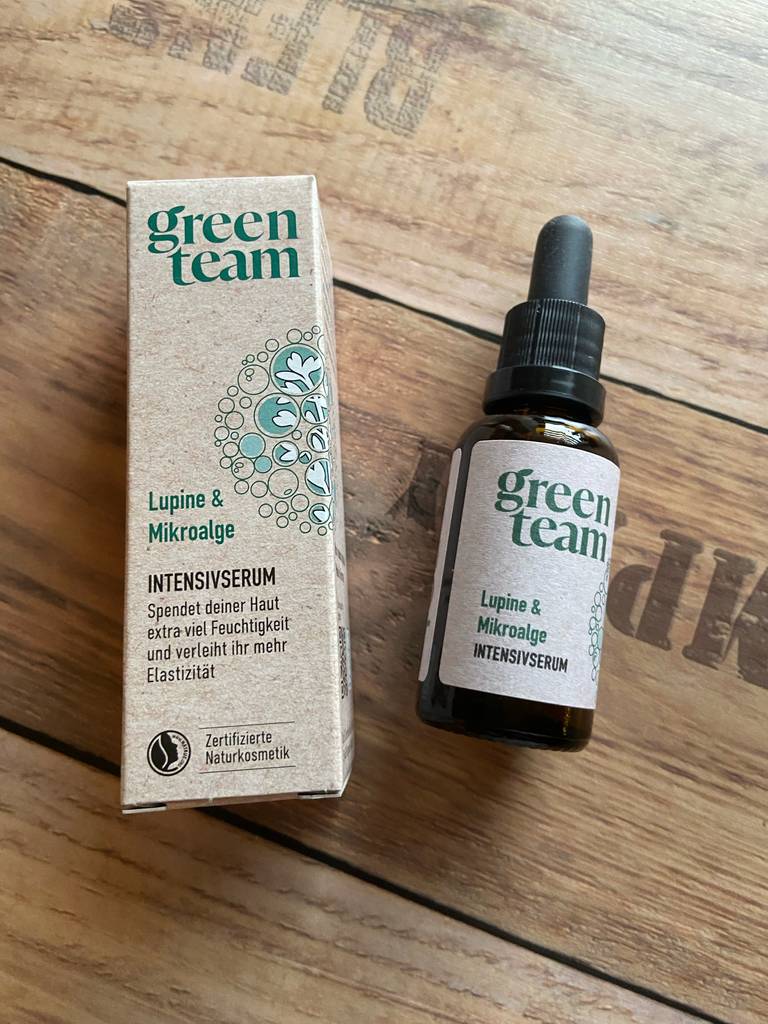 Neben seiner Verpackung liegt die braune Pipetten-Flasche mit der Glättungscreme im Test.