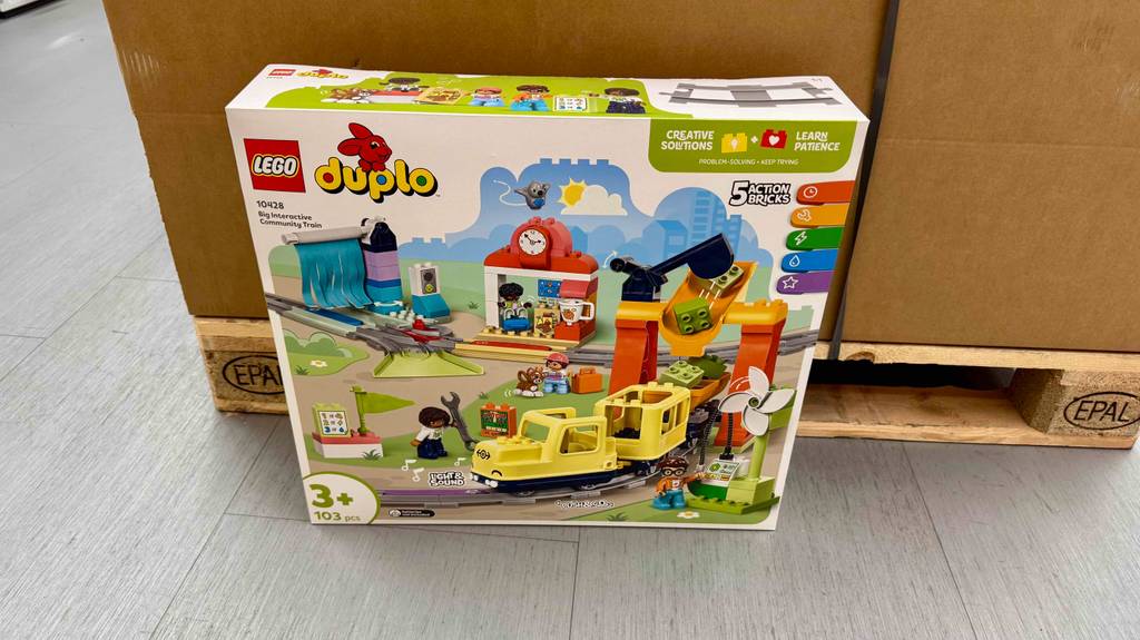 LEGO-DUPLO-Eisenbahnen-Test: Eine Packung mit 103 Einzelteilen steht vor einer Palette, auf der sich ein brauner Karton befindet.