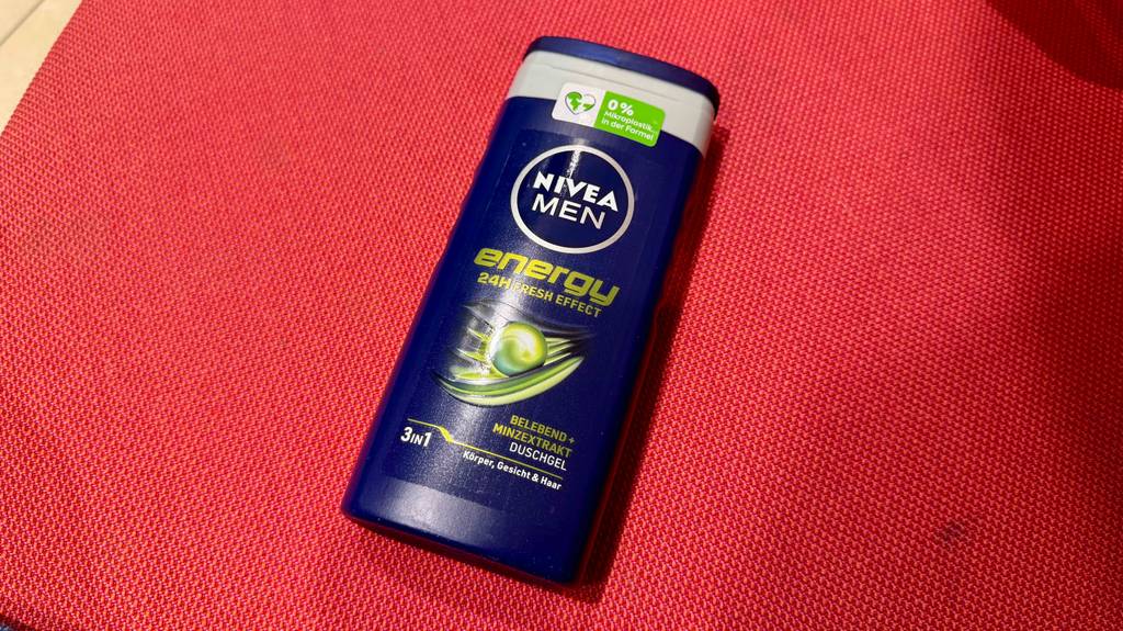 Nivea-Duschgel für Männer im Test: Eine dunkelblaue Quetschflasche liegt auf einem roten Gewebe.