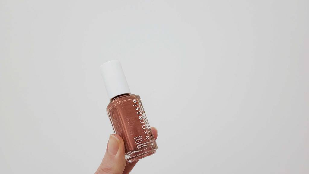 Eine Hand hält einen getesteten Essie-Nagelack der sich in der Flasche befindet.