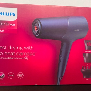 Auf der Vorderseite der Originalverpackung des Philips 5000 Series Haartrockners ist das Produkt samt Zubehör zu sehen.