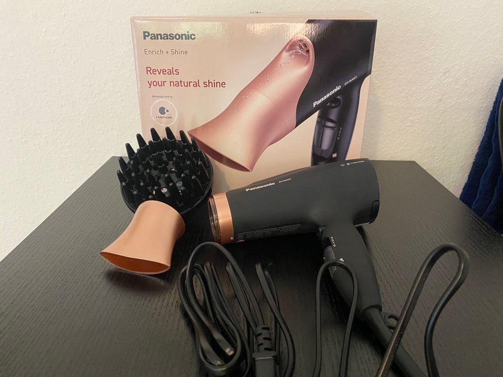 Hier ist der ausgepackte Haartrockner samt Zubehör und Originalverpackung zu sehen.
