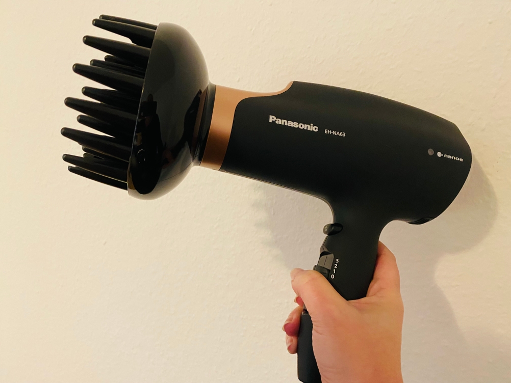 Hier sieht man wie der Haartrockner mit aufgestecktem Diffusor in der Hand gehalten wird.