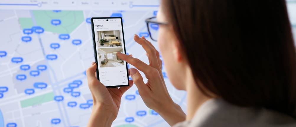 Eine Frau sucht über ein Immobilienportal am Handy nach einer Wohnung.