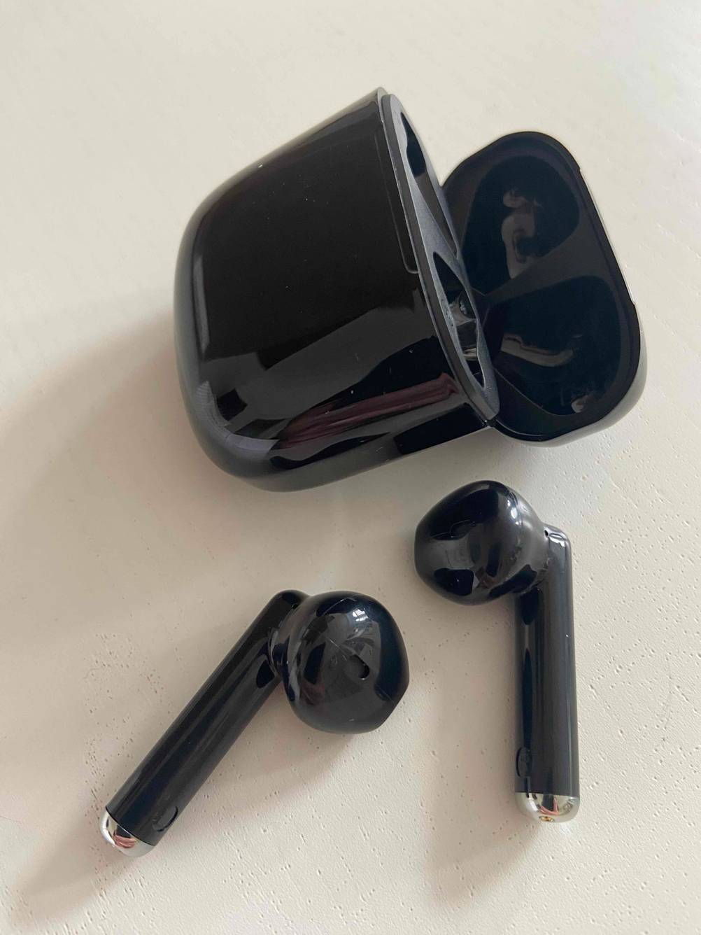 Getestete In-Ear-Bluetooth-Kopfhörer mit Case liegen auf dem Boden. 