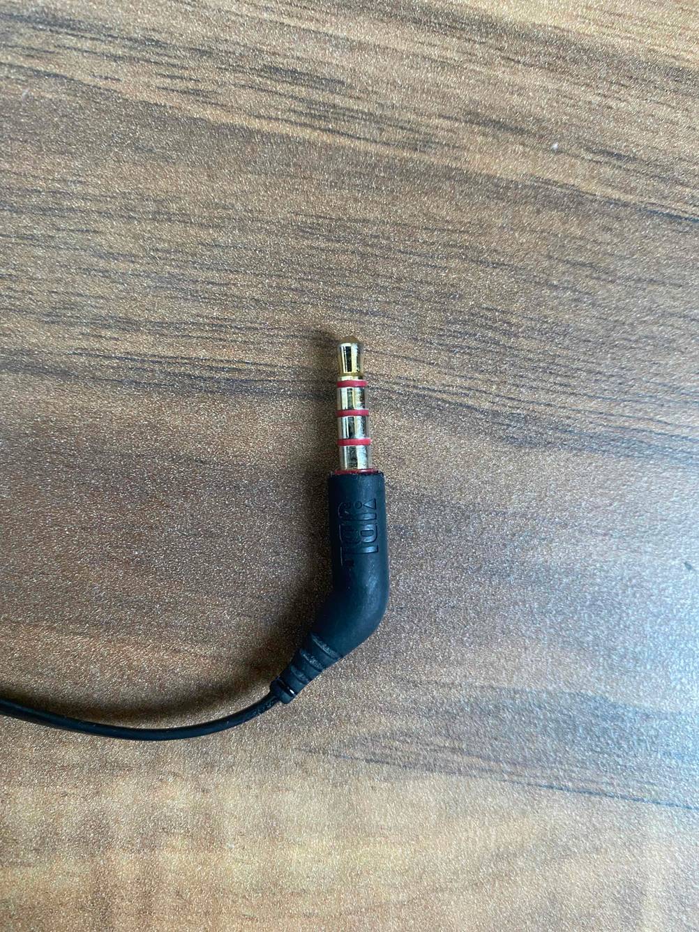 Anschluss von getesteten In-Ear-Kopfhörern-mit-Kabel befindet sich auf einem Holzboden. 
