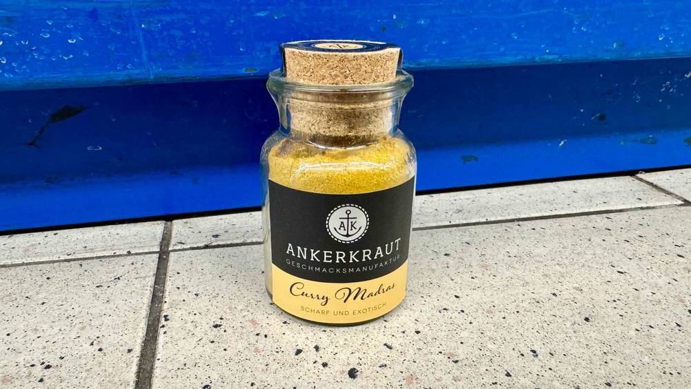 Indische Gewürze-Test: Ein Glas steht vor einem blauen Regal auf dem Boden.