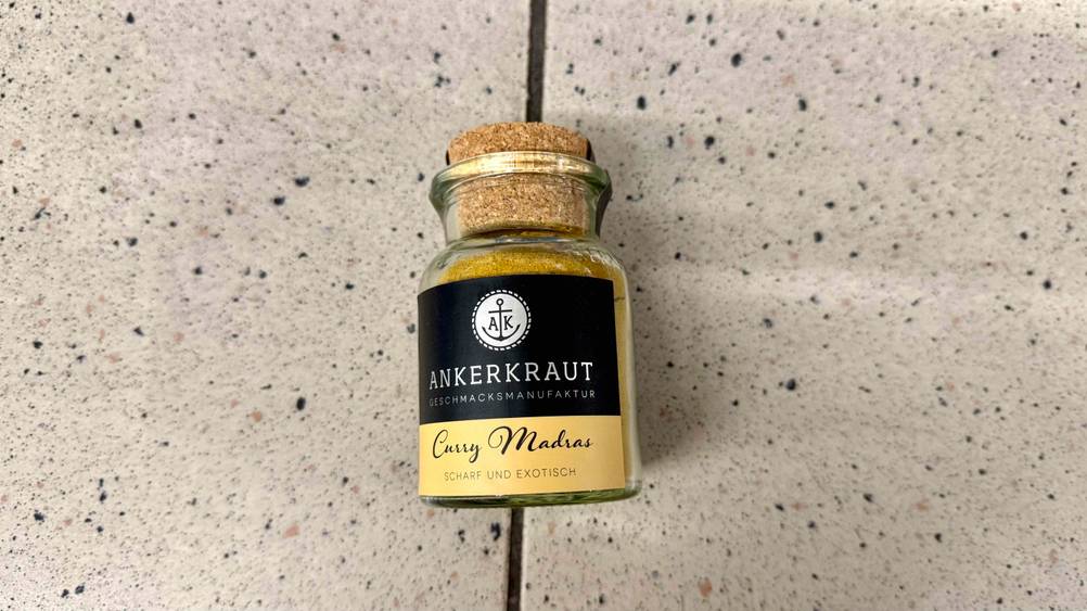 Indische Gewürze im Test: Ein Glas liegt auf einem Fließenboden.