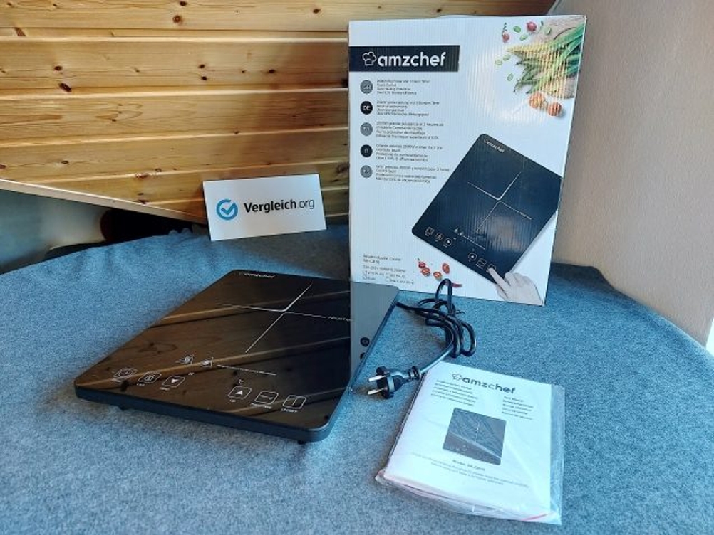 Induktionskochplatte mit Verpackung und Anleitung liegt nebeneinander.