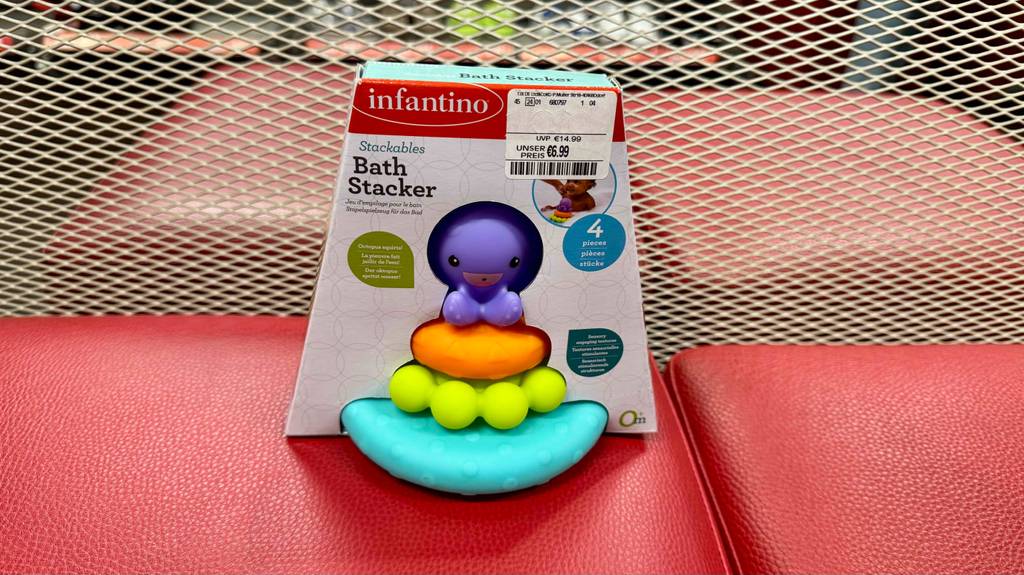 Im Test: Ein Baby-Spielzeug steht in Originalverpackung vor einem Gitter.