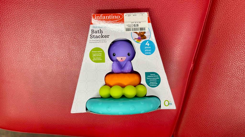 Blick von oben auf ein verpacktes Baby-Spielzeug, das zum testen auf einem roten Hocker liegt.