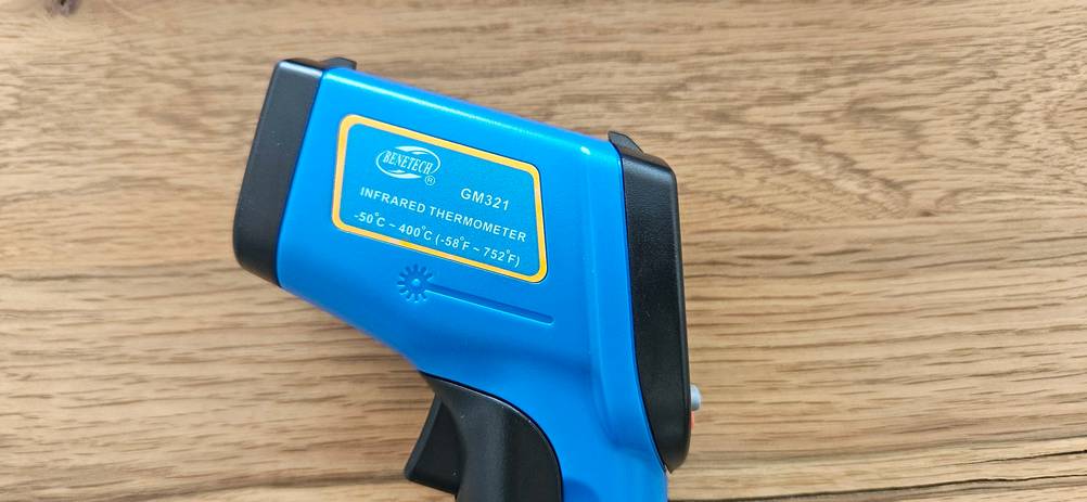 Seitenansicht eines getesteten Infrarot-Thermometers auf einer Holzfläche.