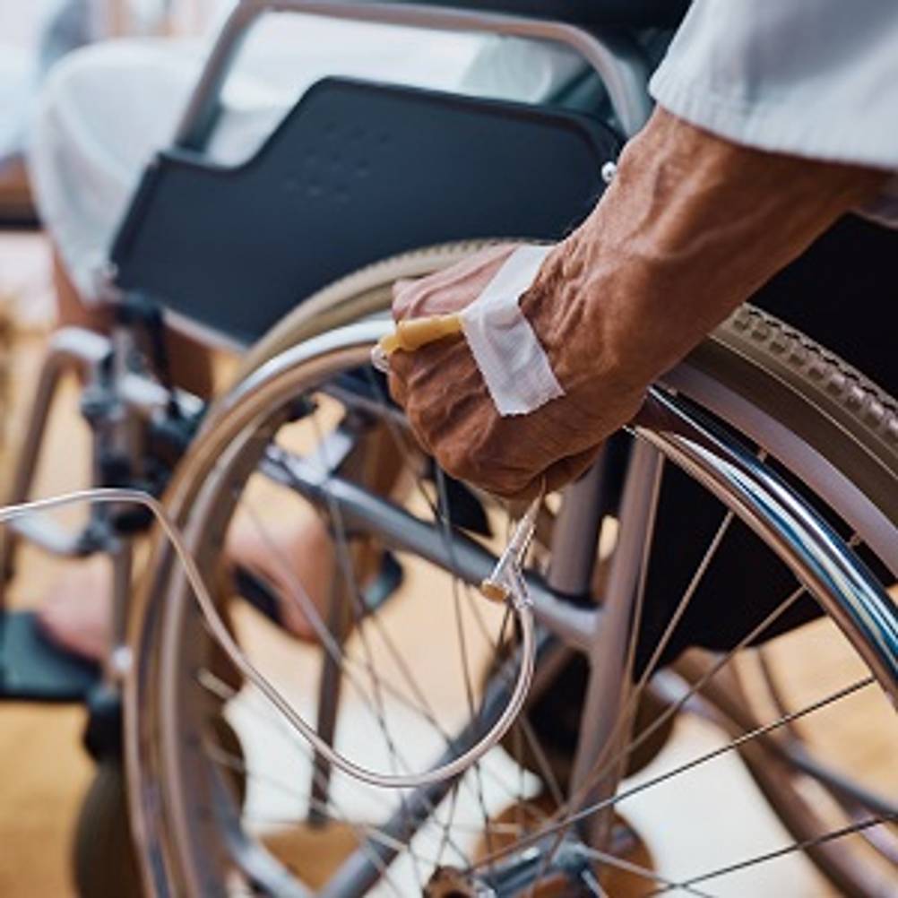 Infusionsständer im Test: Mann im Rollstuhl mit einer Infusion im Arm.