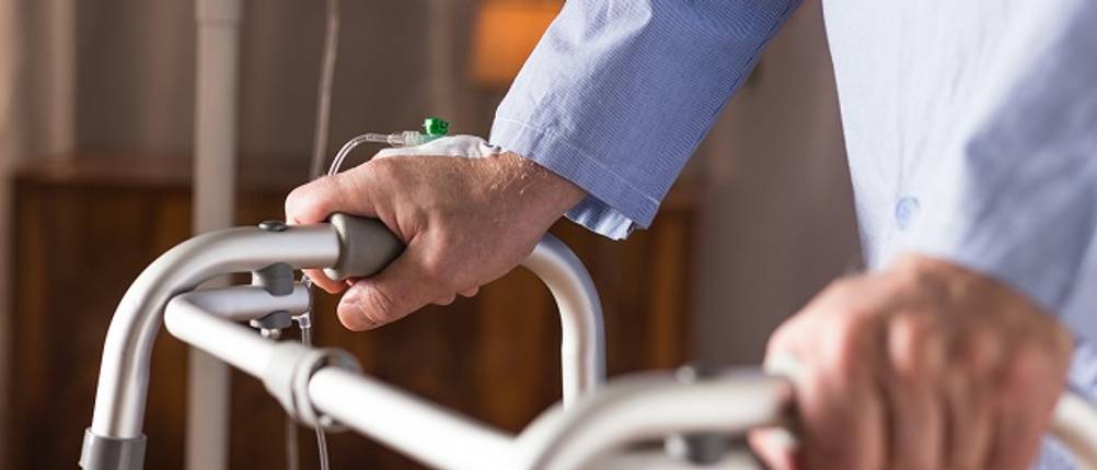 Infusionsständer getestet: Mann, der mit Rollator geht, an dem eine Infusion befestigt ist. 