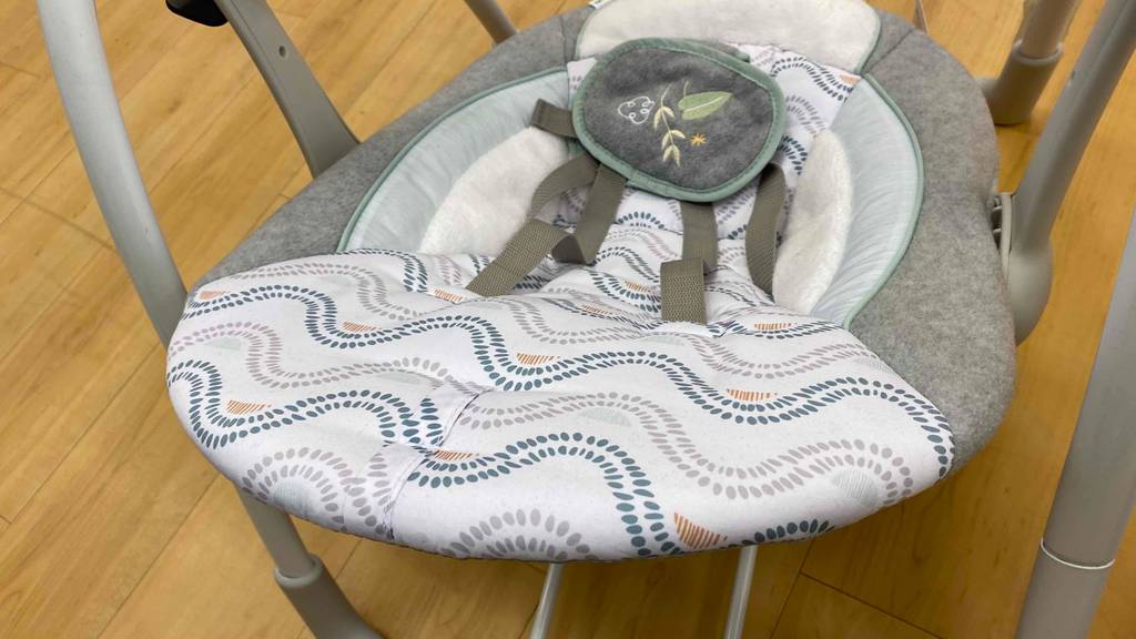 Eine weiß-graue, elektrische Babywippe im Test von oben betrachtet.