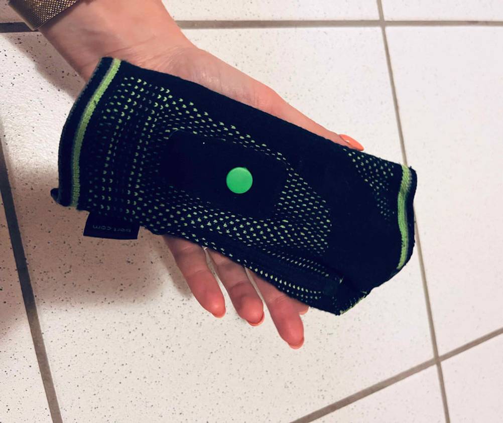 Hand hält Inliner-Protektor im Test inklusive verstellbarer Lasche inklusive Druckknopf.